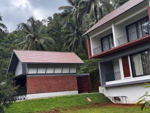 a house with a red roof and two palm trees at GINGY Holidays in Wayanad