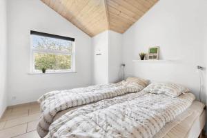 a bedroom with four pillows on a bed with a window at 6824 Allinge - Hammervænget 4 in Allinge