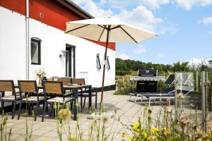 un patio con mesa, sombrilla y piano en 5638 Svaneke - Oksemyrevejen 2 B, en Svaneke