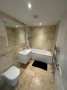 a bathroom with a tub and a toilet and a sink at Epsom High Street Retreat Stylish 1-Bed Flat in Epsom