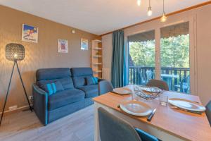 a living room with a blue couch and a table at Studio Élégant Les Orres1650 in Les Orres