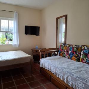 a room with a bed and a couch and a tv at Kitnets a 200 m da praia in Peruíbe