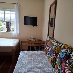 a bedroom with a couch and a tv on the wall at Kitnets a 200 m da praia in Peruíbe +26 photos