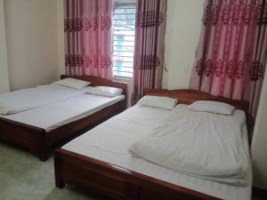 two beds in a room with pink curtains at Nhà nghỉ Ngọc Ánh in Dồng Văn +15 photos