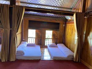 a room with three beds with curtains in it at Nhà nghỉ Ngọc Ánh in Dồng Văn
