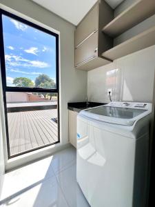 Una cocina con lavavajillas blanco y una gran ventana. en Apartamento Inteiro - 2 Quartos com AC - Wifi 1000mb - Cozinha Completa - 1 Vaga de Garagem - Elevador - Sacada Gourmet - Indicado para Grupos, Hospedes a Trabalho, Família e Pets, en Toledo