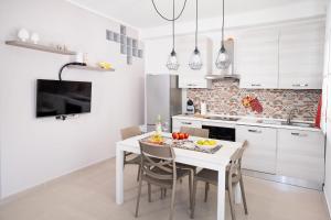 a white kitchen with a white table and chairs at Casa Amelia in Letojanni