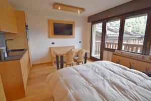 a bedroom with a bed and a table and a television at Presanella View Studio Mhd in Madonna di Campiglio +32 photos