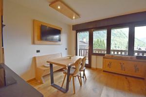 a dining room with a table and a television on the wall at Presanella View Studio Mhd in Madonna di Campiglio