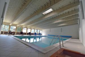 a large swimming pool with chairs in a building at Presanella View Studio Mhd in Madonna di Campiglio