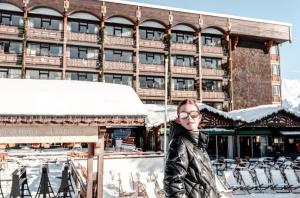a woman standing in front of a hotel in the snow at Alpes Hôtel du Pralong in Courchevel