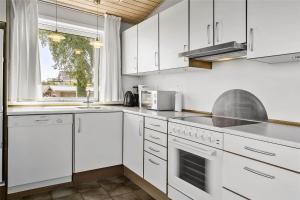 a white kitchen with white appliances and a window at 6682 Allinge - Brunekulvej 2 E in Allinge +9 photos