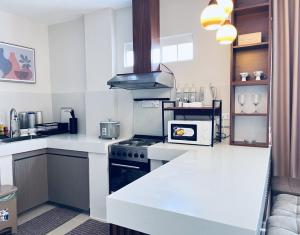 eine Küche mit weißen Arbeitsflächen und einem Herd mit Backofen in der Unterkunft Humble Cocoon1-2BR Unit House Near Inflatable Island & Subic Bay Yacht in Subic