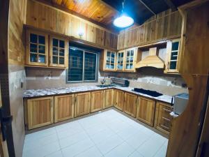 een keuken met houten kasten en een witte tegelvloer bij 4BHK Dunga Gali in Dunga Gali