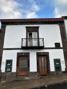 a white building with a balcony and doors at A Mercearia in Água de Pau