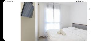 Un dormitorio con una cama con almohadas blancas y un televisor. en אכזיב על הים, en Nahariyya