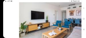 sala de estar con TV y sillas azules en אכזיב על הים, en Nahariyya 2 fotos más