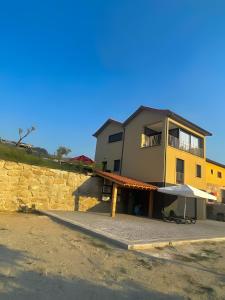 un edificio giallo con un ombrello davanti di Serração House - Gerês a Rio Caldo