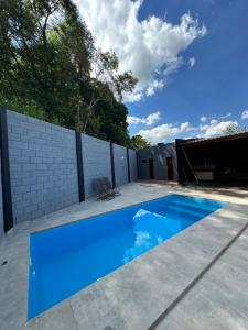 a blue swimming pool on a patio with a fence at Athenas Chacará in Jacareí