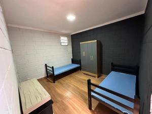 a small room with two beds and a locker at Athenas Chacará in Jacareí