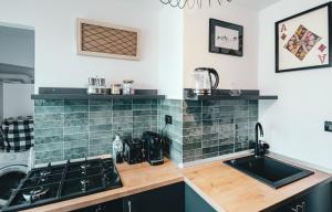 a kitchen with green tiles on the wall and a sink at Noctis Nine in Curtea de Argeş