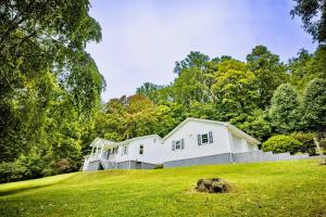 a white house on a grassy hill with trees at 17 Min to NRG | Grill | Huge Yard | Private | Cozy in Oak Hill