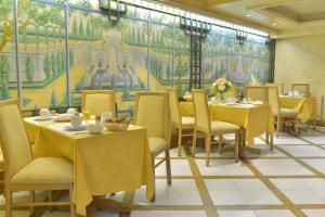 une salle à manger avec des tables et des chaises ainsi qu'une fresque murale. dans l'établissement Hôtel Renoir Montparnasse, à Paris