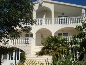 Cette grande maison blanche dispose d'un balcon blanc. dans l'établissement Apartments Rora, à Rogoznica
