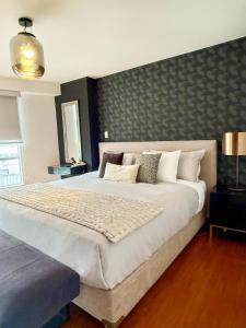 Un dormitorio con una cama grande con una pared. en Departamento Ricardo Palma, en Lima