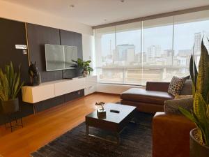 Una sala de estar con un sofá y un televisor. en Departamento Ricardo Palma, en Lima