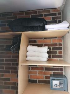 a shelf with towels and a clock in front of a brick wall at La 70, Laureles Condo, Cold AC in Medellín