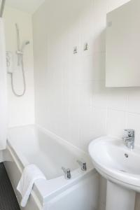 Un baño blanco con bañera y lavabo. en Bright & Spacious 2 Bedroom Flat, en Edimburgo