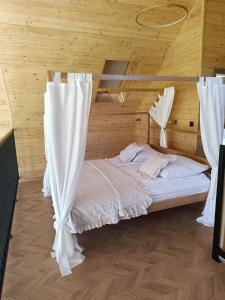 a bed with white curtains in a wooden room at Villa Brzezinów in Tłuszcz