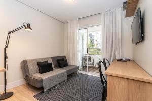 a living room with a couch and a desk at Flat Parque do Ibirapuera - Jardins in São Paulo