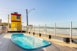 a hot tub on a patio next to the beach at Duplex pé na areia com vista deslumbrante RAT001 in Porto Belo