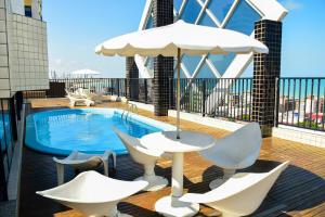 ein Balkon mit Pool und Stühlen und Sonnenschirm in der Unterkunft Flat com piscina em Tambaú in João Pessoa
