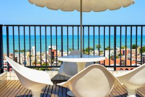 einen Balkon mit Stühlen, einem Tisch und Meerblick in der Unterkunft Flat com piscina em Tambaú in João Pessoa