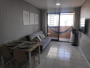ein Wohnzimmer mit Sofa und Tisch in der Unterkunft Flat com piscina em Tambaú in João Pessoa