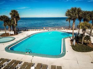 a swimming pool next to the ocean with palm trees at Bay Club of Sandestin in Destin