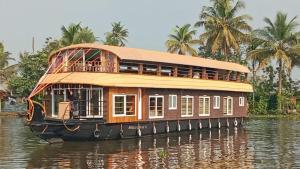 una casa flotante en el agua con palmeras en el fondo en Vistara Backwater Cruise, en Alleppey