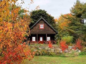 una piccola casa con un muro di pietra davanti di Enchanted Forest Cabin a Winterport