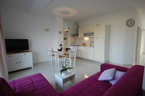 a living room with a purple couch and a kitchen at Apartments Curicta 1 in Krk