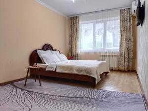 a bedroom with a bed and a window at Nectar Apartments in Aktobe