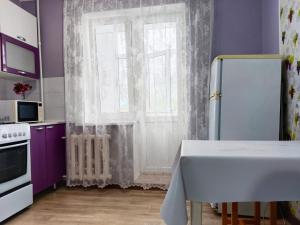 a kitchen with purple walls and a door with a window at Nectar Apartments in Aktobe