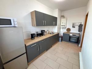 eine Küche mit grauen Schränken und einem Kühlschrank in der Unterkunft Komfortable Ferienwohnung im Herzen von Stendal in Stendal