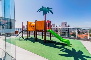 a playground on the roof of a building with a palm tree at Condomínio Vila do Centro Bombinhas in Bombinhas