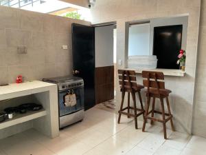 cocina con 2 taburetes y fogones en Casa Coralite, en Santa Marta