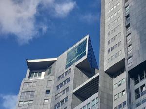 ein hohes Gebäude mit blauem Himmel im Hintergrund in der Unterkunft Sea Towers! SKY PENTHOUSE! Panoramic SEA & CITY VIEWS from Glass Corner TRIANGLE! 28 TOP Floor! Terrace! Short & Long Stay! Parking! Sailing in the heaven feels like a King! in Gdynia