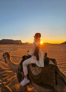 a woman riding on the back of a camel in the desert at Rum STAR luxury camp in Wadi Rum