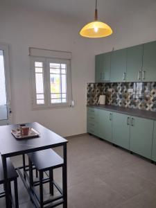 a kitchen with green cabinets and a table and chairs at Villa Desire in Korinos